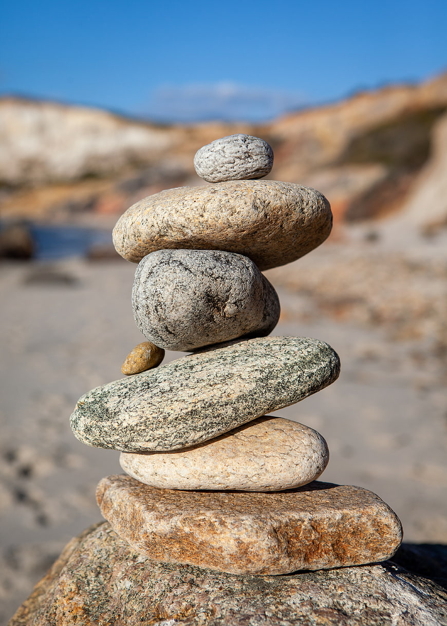 Stacked Beach Stones on Sand with Blurred Coastal Background