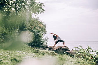 Woman practicing yoga outdoors by the sea