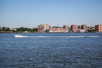 Motorboat Cruising on River with City Skyline Background