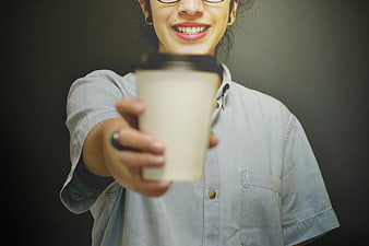 Woman Offering Coffee Cup to Camera