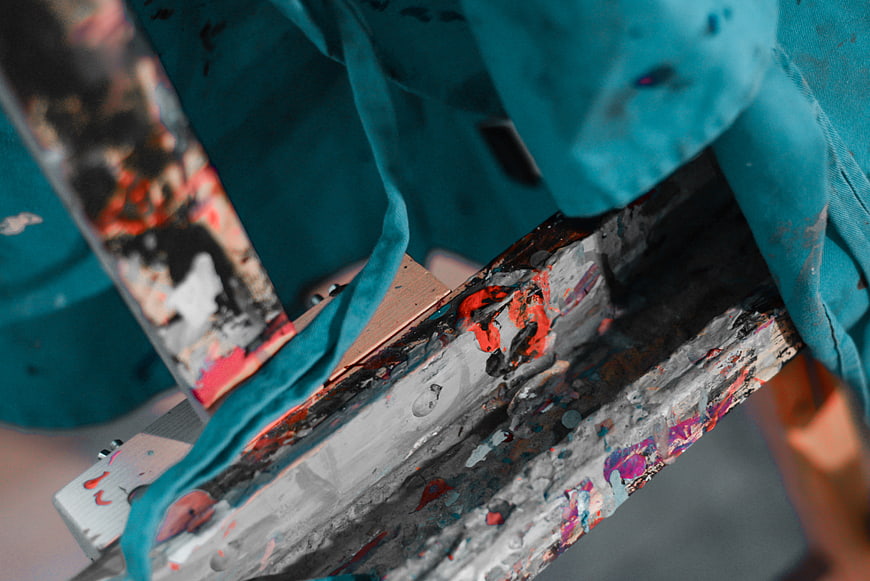 Close-up of paint-splattered wooden easel with teal cloth