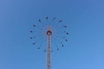 Tall swing ride at fairground against clear blue sky