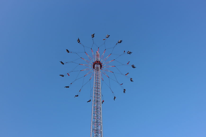 Tall swing ride at fairground against clear blue sky