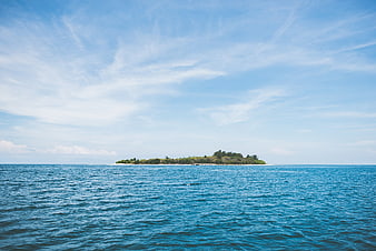 Tropical island with lush green trees in blue ocean