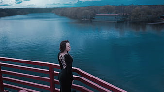 Woman in Black Dress Standing by Red Railing Over River