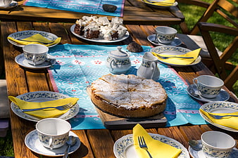 Outdoor Garden Tea Party Table Setting With Apple Cake And Blue Floral Tablecloth