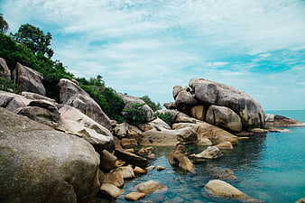 Scenic tropical rocky coastline with turquoise ocean water and blue sky