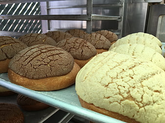 Freshly baked conchas on a metal bakery rack