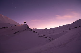 Lone Hiker with Headlamp on Snowy Mountain Ridge at Twilight