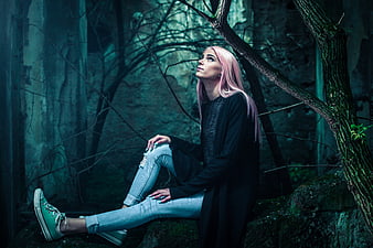 Pink-haired woman sitting in dark moody forest ruins