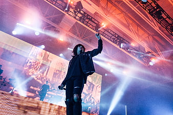 Concert performer on stage with dramatic lighting and large LED screen