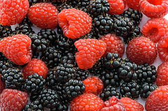 Close-up of fresh raspberries and blackberries on white background