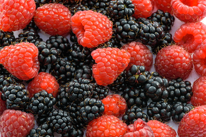 Close-up of fresh raspberries and blackberries on white background