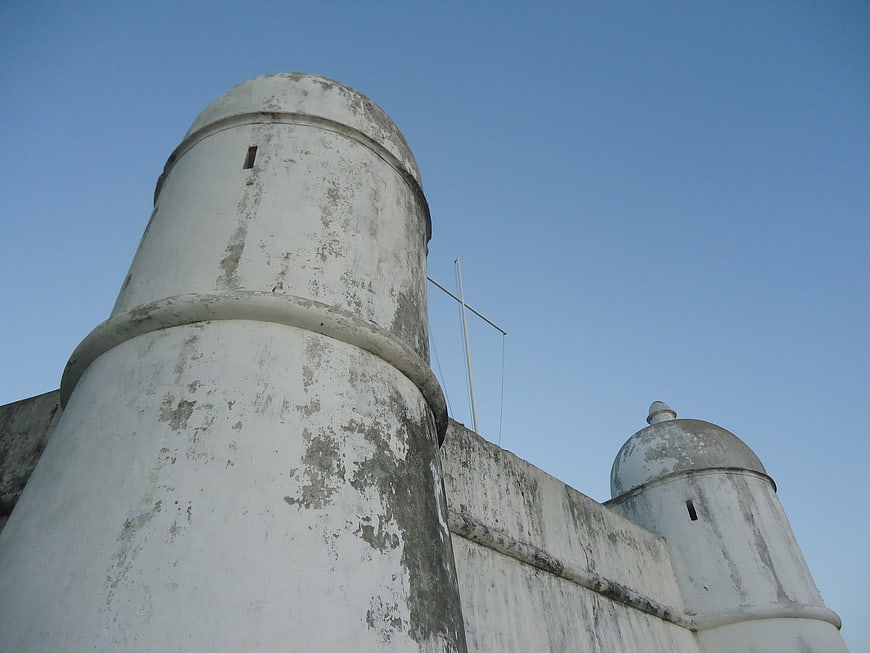 Low angle view of weathered white fortress towers against blue sky