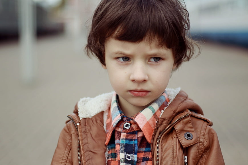 Portrait of a serious young boy in a brown jacket