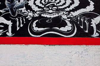 Black and white graffiti mural with red stripe on brick wall