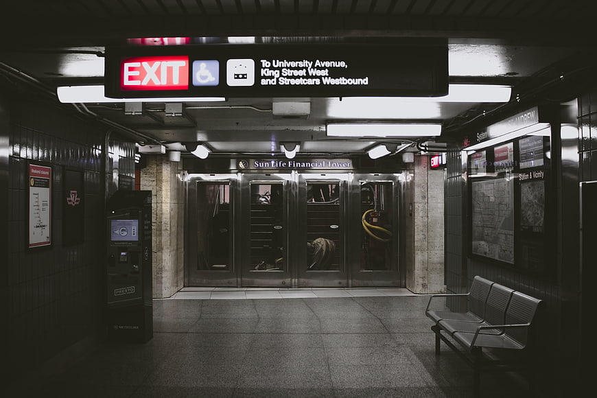 Empty subway station exit with illuminated signage and bench