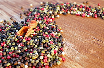 Colorful peppercorns and wooden scoop on rustic wood