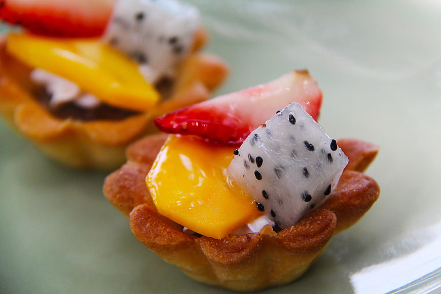 Close-up of fresh fruit tartlets with mango, strawberry, and dragon fruit