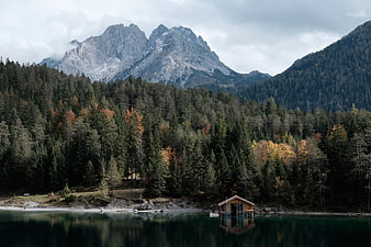 Serene Alpine Lake with Wooden Cabin and Autumn Forest