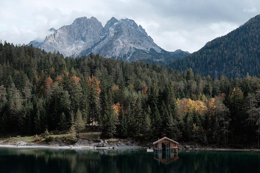 Serene Alpine Lake with Wooden Cabin and Autumn Forest
