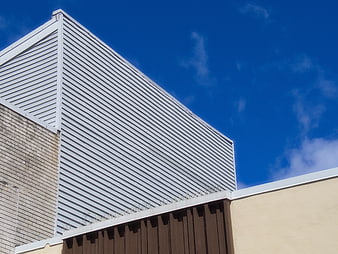 Modern industrial building facade with corrugated metal and blue sky