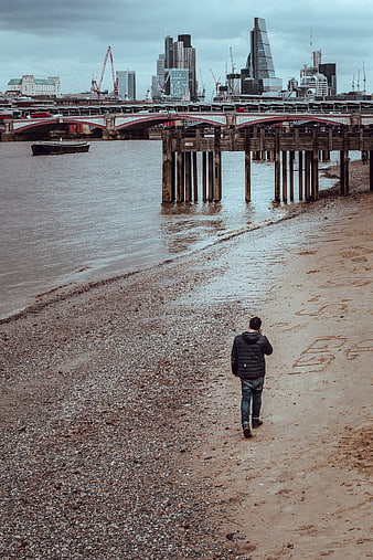 Man Walking on Thames Shore with London Skyline