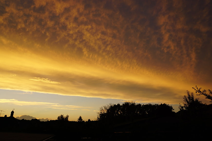 Dramatic golden sunset sky with textured clouds over silhouette