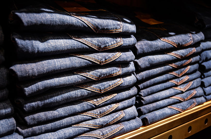 Stacks Of Folded Blue Denim Jeans On Retail Shelf
