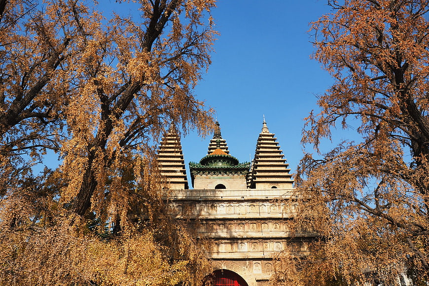 Ancient stone pagoda framed by golden autumn trees