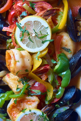 Close-up of seafood stew with shrimp, mussels, peppers, and lemon