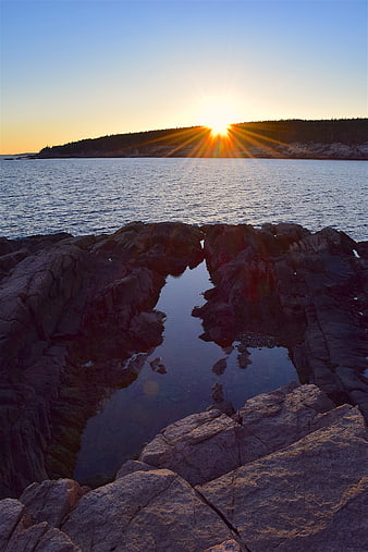 Sunset over rocky coastline with tide pool reflection