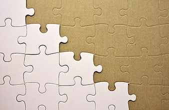 White Jigsaw Puzzle Pieces On Brown Cardboard Background