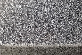 Close-up of salt spray texture on a dark car hood