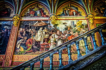 Historical mural paintings in a grand ancestral gallery with staircase