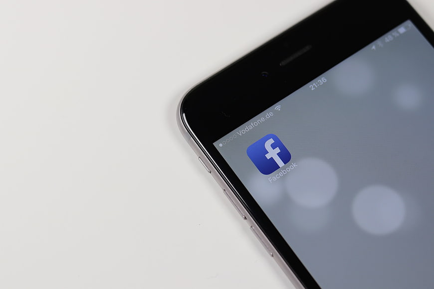 Close-up of smartphone screen displaying Facebook app icon on white background