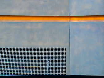 Abstract industrial metal facade with perforated pattern and orange stripe