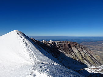 Snowy Mountain Peak with Colorful Rock Strata and Blue Sky