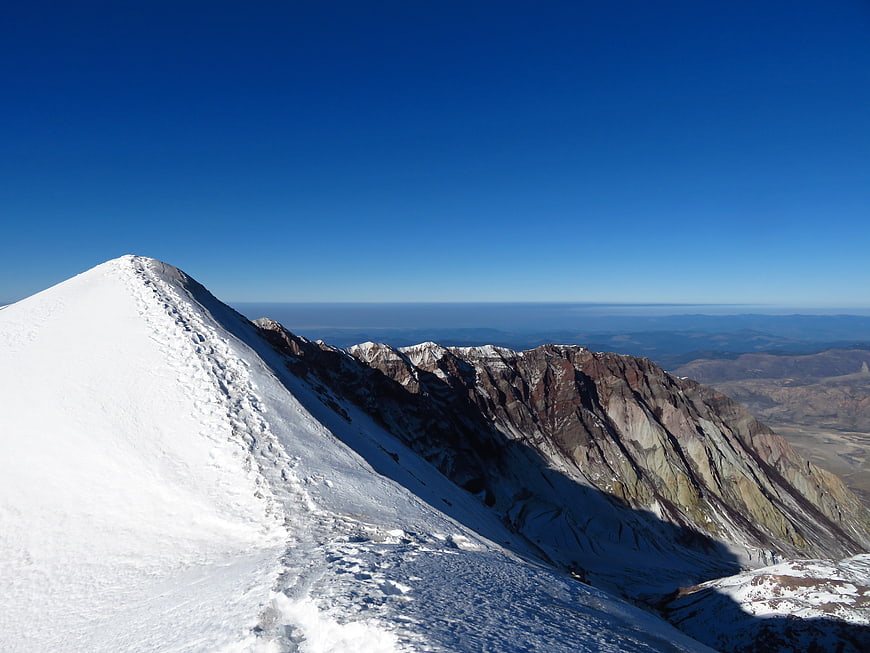 Snowy Mountain Peak with Colorful Rock Strata and Blue Sky