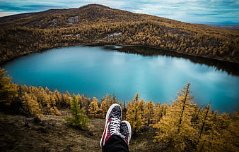 Hiker's feet overlooking turquoise alpine lake in autumn