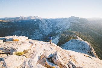 Hiker standing on granite ridge overlooking mountain valley