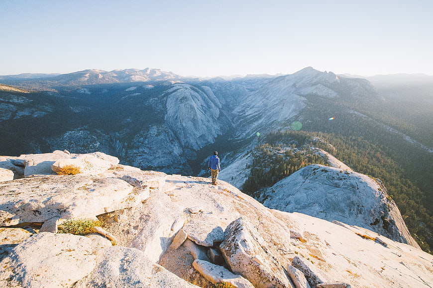 Hiker standing on granite ridge overlooking mountain valley