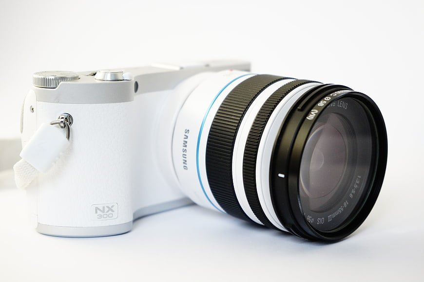 White Samsung NX300 Mirrorless Camera with Zoom Lens on White Background
