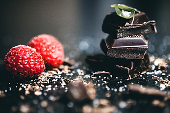 Dark Chocolate Pieces and Raspberries on Black Background