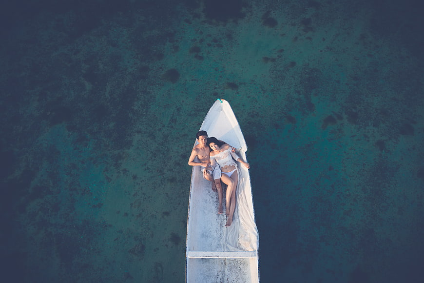 Aerial view of couple relaxing in boat on turquoise ocean