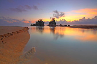 Serene Beach at Dawn with Rock Formations and Reflections