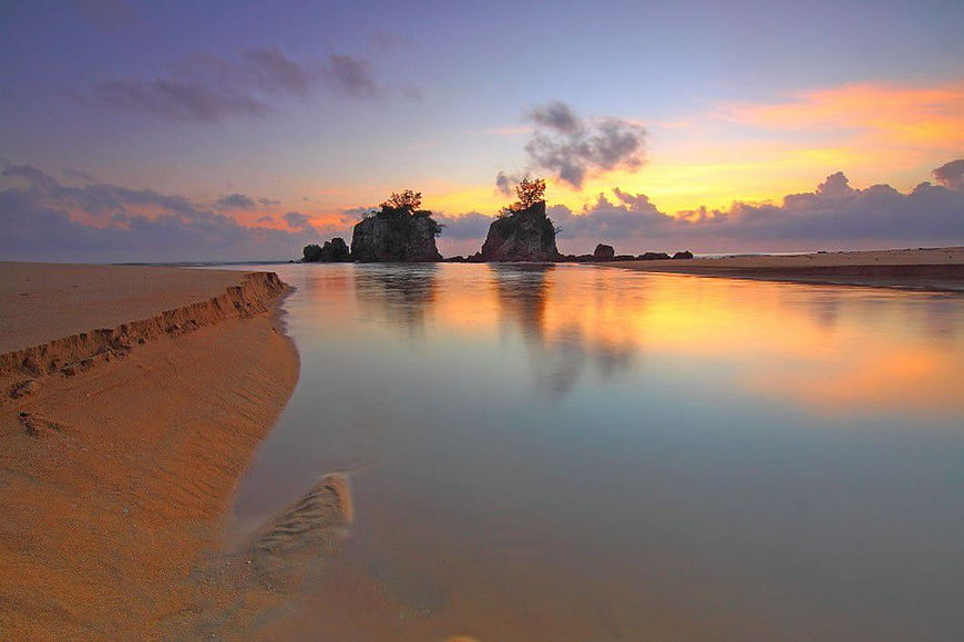 Serene Beach at Dawn with Rock Formations and Reflections