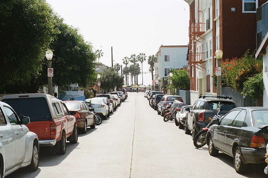 Sunny residential street with parked cars and palm trees