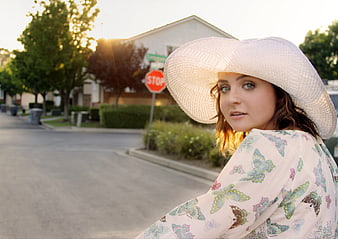 Woman in White Hat and Butterfly Shirt on Suburban Street