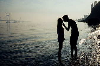 Silhouette of couple kissing on beach at sunset